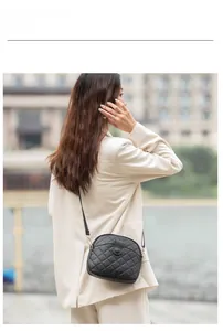 Outdoor shot of a black quilted crossbody shell bag worn by a model in a street setting
