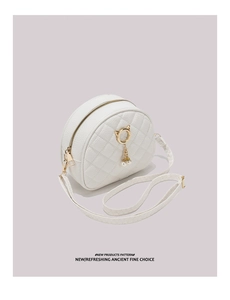 Detailed view of white quilted bag featuring a gold cat-ear ring and pearl pendant