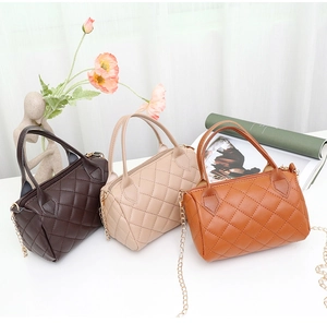 Détails de petits sacs polochons matelassés en marron, blanc et orange avec chaînes dorées