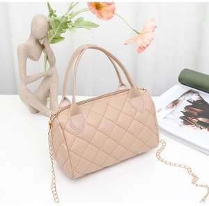 Gros plan du sac Boston matelassé beige avec chaîne dorée et texture élégante
