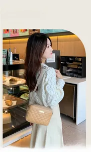 Detail of light beige quilted crossbody bag with golden hardware and adjustable strap