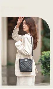 Black quilted bucket bag with gold emblem shown on an Asian female model in outdoor setting