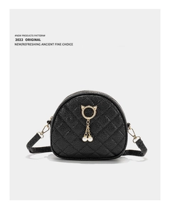 Close-up of black quilted crossbody bag with gold cat-ear ring and pearl pendant detail