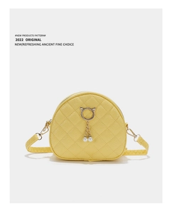 Detail of yellow quilted crossbody bag with golden cat ear ring and pearl charms