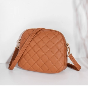 Close-up of caramel shell handbag featuring quilted lattice pattern and golden zipper detail