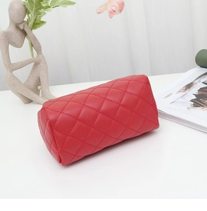 Détail d'une trousse de maquillage rouge en similicuir avec texture à surpiqûres losanges