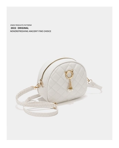 Detail of white quilted crossbody bag with golden cat-ear ring and pearl charms