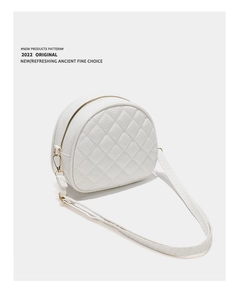 Close-up of white crescent crossbody bag with quilted lychee leather and gold hardware