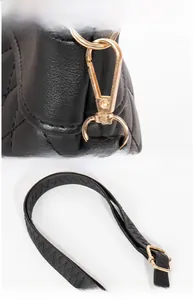 Detail of gold metal hook and Z-stitch black leather strap on quilted bucket bag