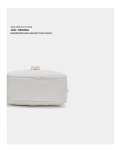 Detailed macro view of white lychee pattern leather bag featuring large pearl clasps
