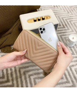 Close-up of beige quilted long wallet with V-pattern stitching held by a woman