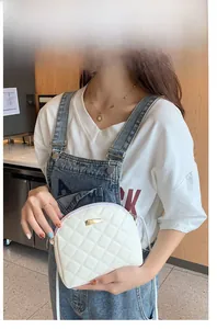 Dettaglio di una borsa a conchiglia trapuntata bianca con finiture dorate su modella
