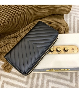 Close-up of black long wallet with V-shaped quilting and golden double zippers