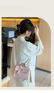 Détail du sac bandoulière rose à texture croco avec fermoir rotatif en métal doré