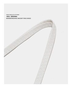 Close-up of white embossed leather strap with zigzag stitching on crossbody bag