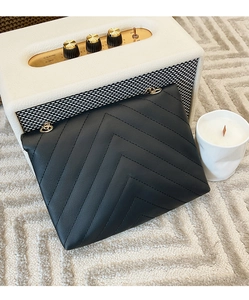Detail of black V-quilted faux leather bag with gold rings and stylish matte finish