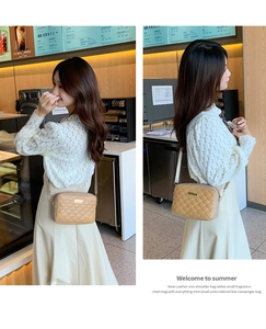 Detailed view of a light khaki quilted crossbody bag with elegant embroidery and metal tag
