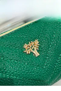 Close-up of green pebble leather with V-shaped quilting and golden tree metal clasp