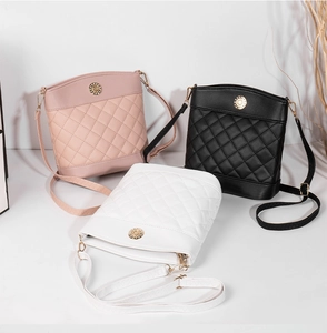 Close-up of quilted bucket bags in pink, black and white with gold metal buckles