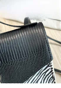 Détail du cuir gaufré lézard et motif zébré sur un petit sac à main carré à rabat