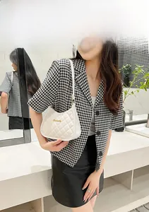 White quilted hobo bag with gold metal logo worn by a model in a houndstooth blazer