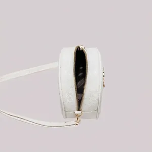 White round leather crossbody bag with pebble texture and golden zipper closure