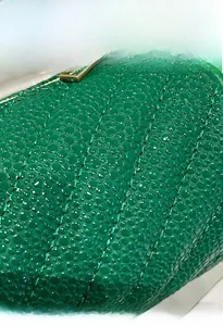 Detail of green textured fabric with quilted pearl grain and glossy finish on a round bag