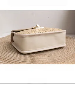 Detail of woven straw and beige PU leather shoulder bag with golden round swivel lock