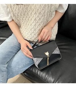 Détail du sac à motif lézard avec imprimé zèbre et fermoir doré en forme de chat perlé