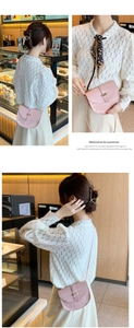 Detail of light pink crocodile pattern saddle bag with gold clasp on a crossbody strap