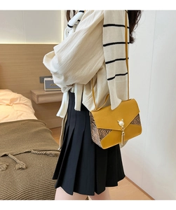 Détail du sac à main en cuir jaune avec bordure animalière et breloque chat en perles