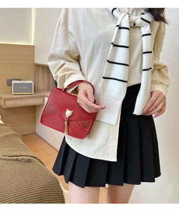 Détail du sac rouge en simili cuir avec rayures tigrées et breloque chat en perle dorée