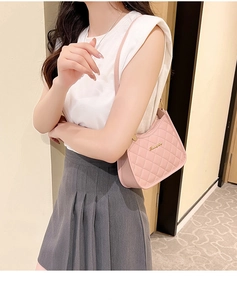 Close-up of pink quilted shoulder bag with gold metal logo and sleek leather strap