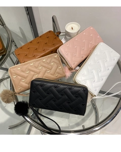 Close-up of quilted PU leather wallets with heart embroidery, pompom charms and wristlet