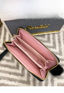 Detail view of long black wallet with pink interior showing card slots and zipper compartment