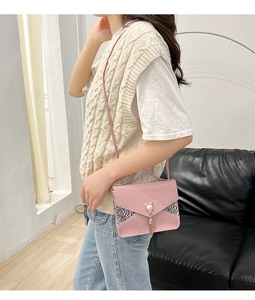 Sac bandoulière rose avec détails zébrés et un pendentif chat en perle avec gland