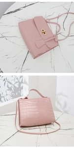 Détail d'un mini sac rose à motif crocodile avec fermoir doré sur un fond en marbre