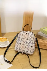 Close-up of beige plaid mini backpack showing leather texture and golden metal hardware