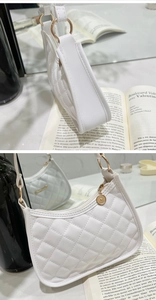 Close-up of white quilted crescent bag with gold zipper and smooth faux leather texture