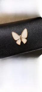 Detail of black PU leather bag with white butterfly metal ornament and magnetic snap