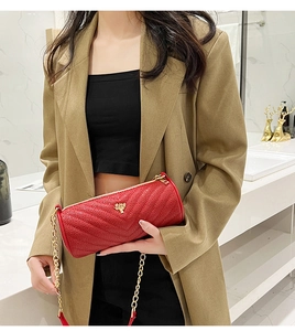 Red cylindrical chain bag with V-quilt pattern and gold tree logo shown on model