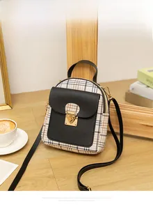 Close-up of a plaid canvas and black leather mini backpack on a cozy wooden table