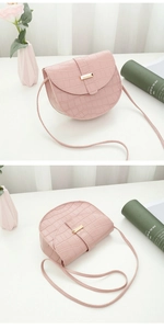 Pink crocodile pattern saddle bag featuring a gold metal buckle and leather shoulder strap