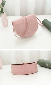 Close-up of pink faux crocodile skin texture on a mini saddle bag with shoulder strap