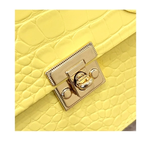 Macro detail of crocodile texture yellow leather bag with a golden metal lock closure