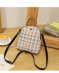 Close-up of a mini plaid backpack on a wooden table with coffee and vintage books