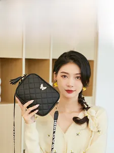 Close-up of black quilted crossbody bag with golden butterfly charm and tassel detail