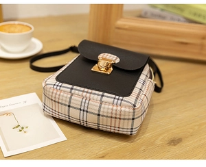 Detail of vintage mini crossbody bag with plaid fabric and gold buckle on a table