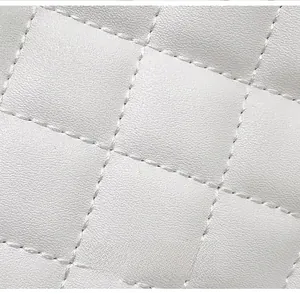 Macro detail of white diamond quilted synthetic leather texture on a shoulder bag