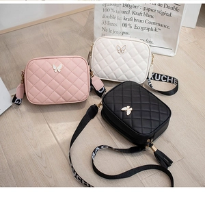 Close-up of quilted crossbody bags with butterfly buckles and wide lettered straps